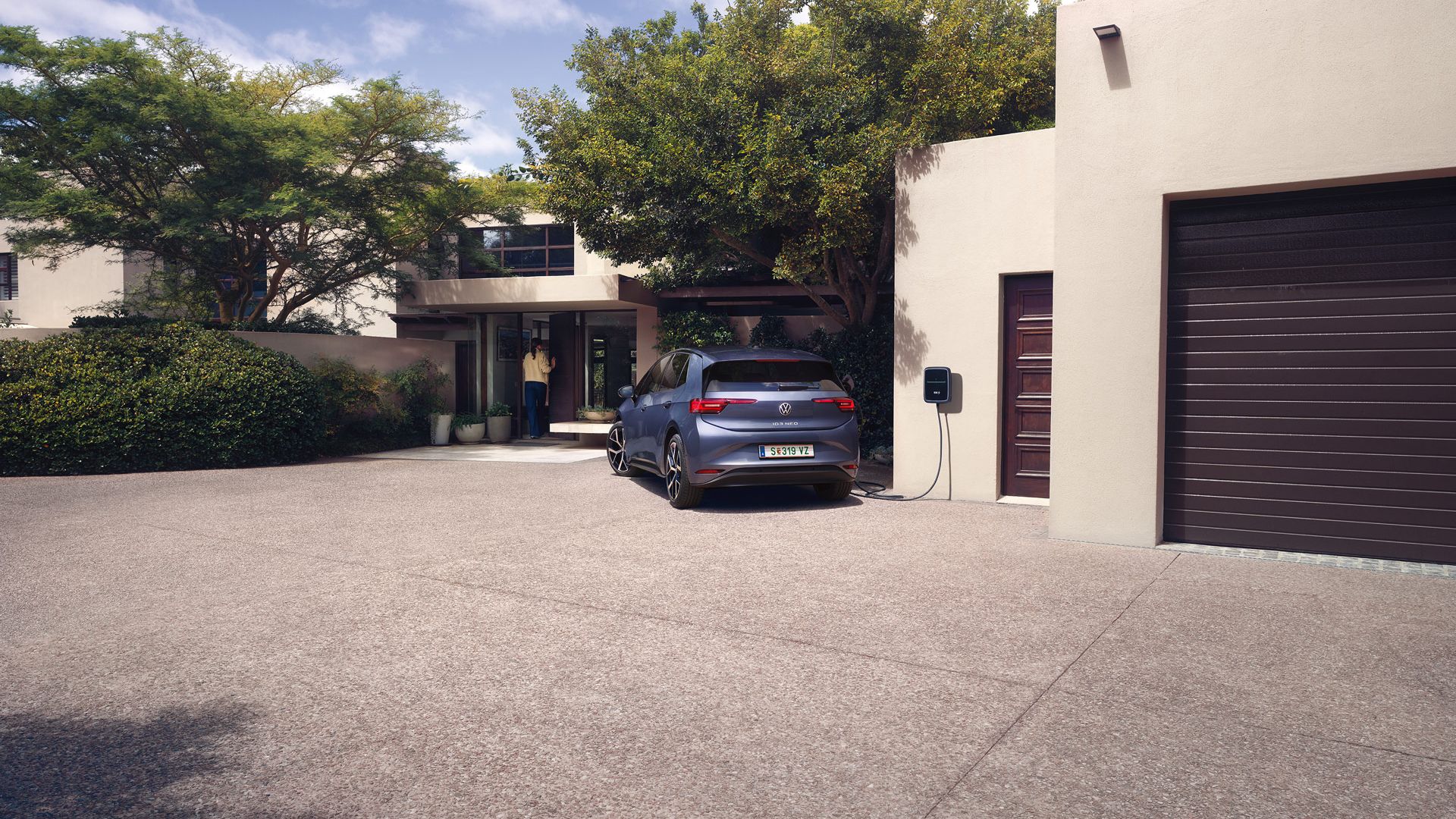 Ein blauer VW ID.3 Neo lädt an einer Wallbox vor einem Einfamilienhaus