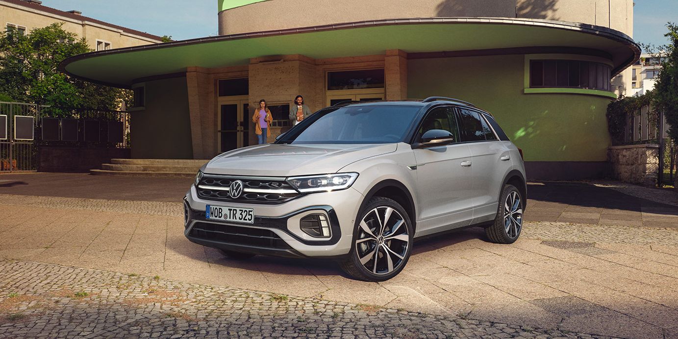 VW T-Roc R-Line in weiß vor einem Gebäude, Front und Seite sichtbar