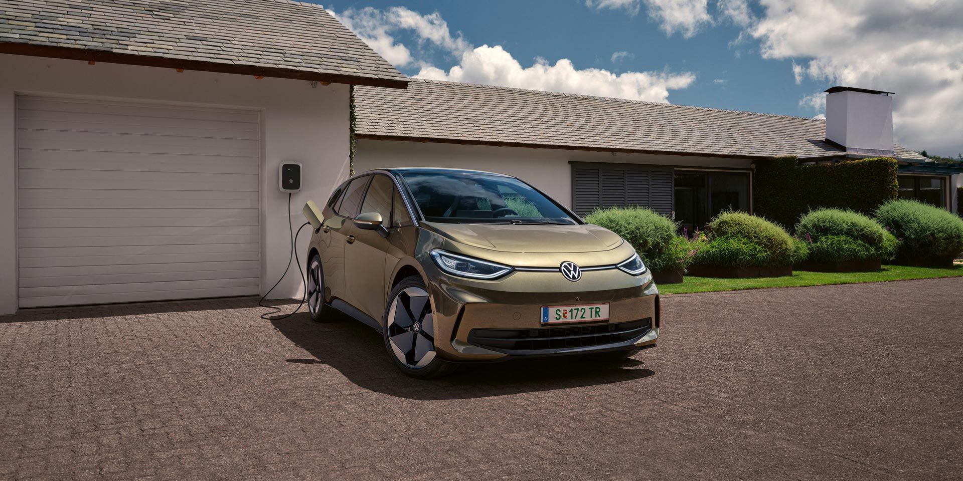 Der VW ID.3 wird an einer Wallbox geladen im Hintergrund ein Einfamilienhaus