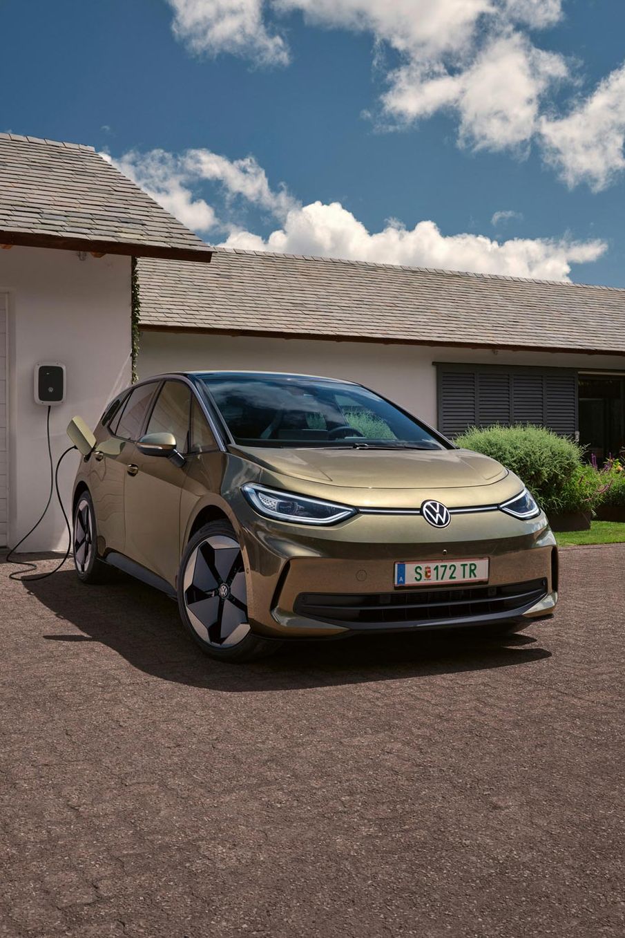 Der VW ID.3 wird an einer Wallbox geladen im Hintergrund ein Einfamilienhaus