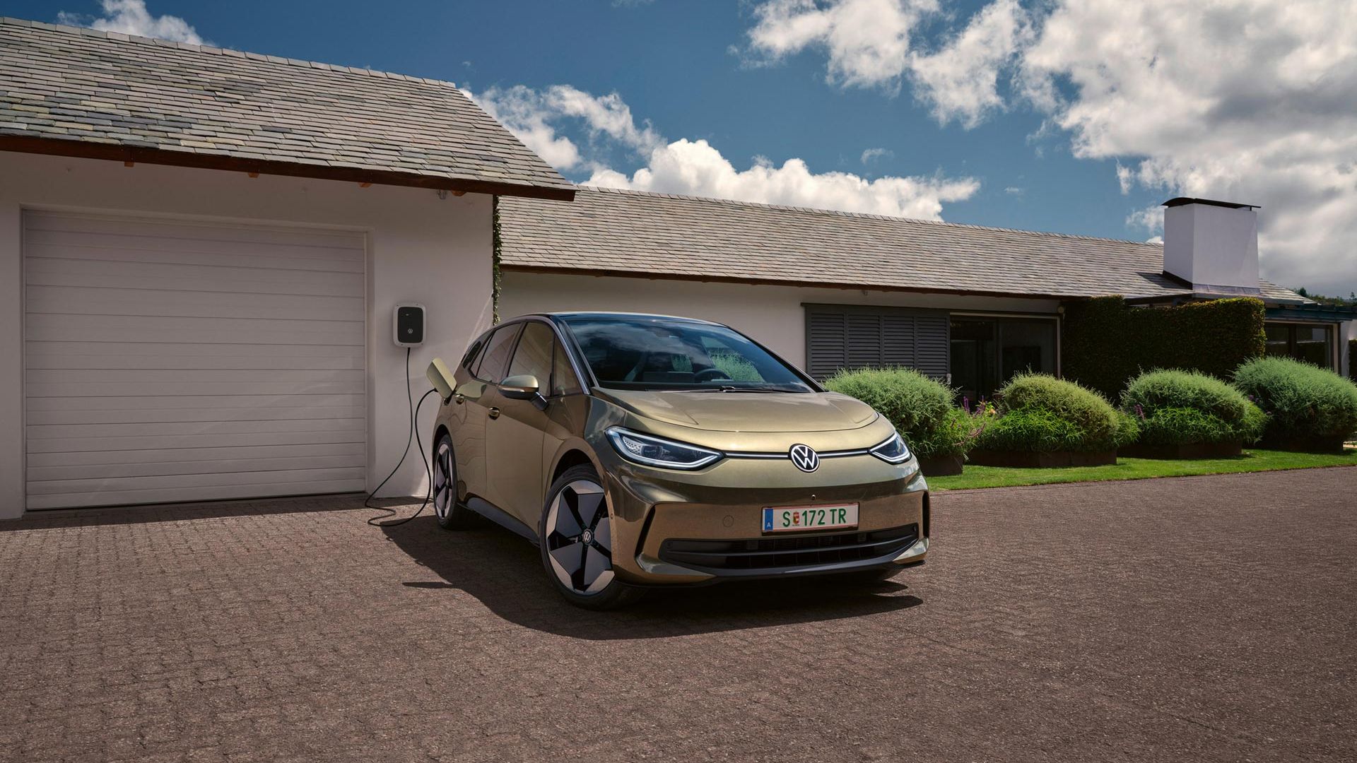 Der VW ID.3 wird an einer Wallbox geladen im Hintergrund ein Einfamilienhaus