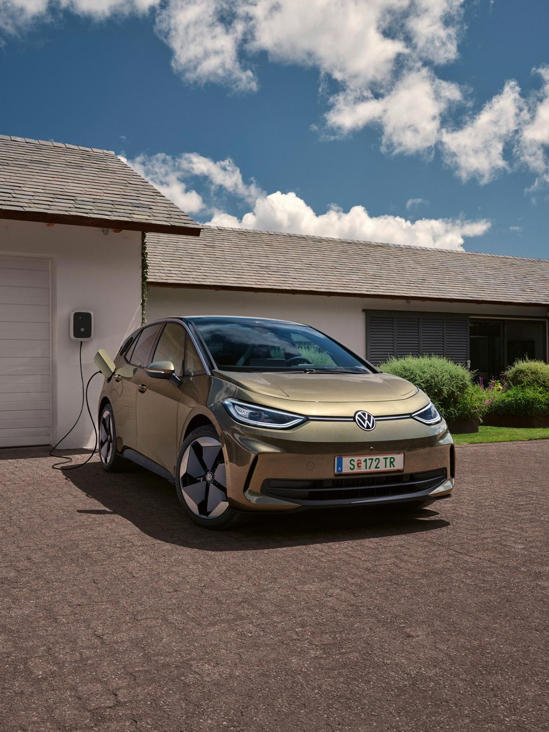 Der VW ID.3 wird an einer Wallbox geladen im Hintergrund ein Einfamilienhaus