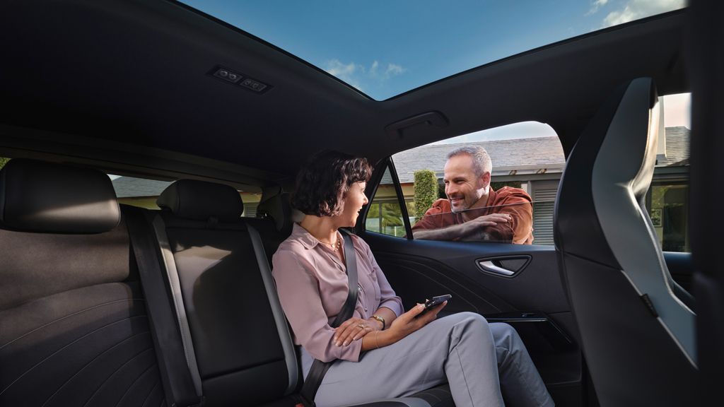 Eine Frau sitzt auf der Rückbank des VW ID.3 und redet mit einem Mann